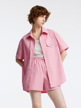 A lady wears a tank top and a pink shirt.